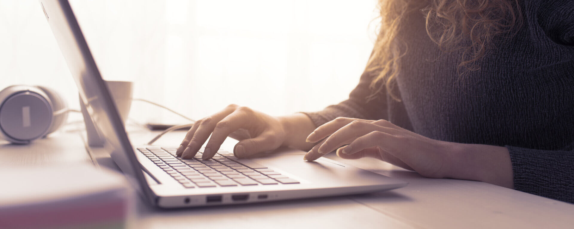 Woman sitting at desk and connecting with her laptop, she is working and typing on the keyboard, hands close up