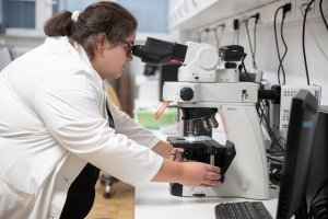 Oprema za proizvodnjo bioloških substanc in njihovo detekcijo: raziskovalka pri delu z mikroskopom